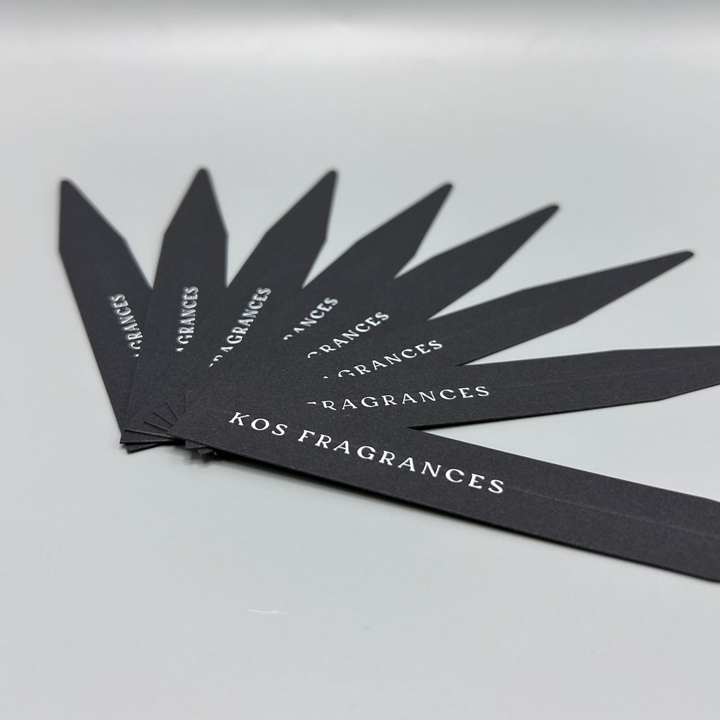 Black smelling strips with 'KOS FRAGRANCES' branding on a gray background