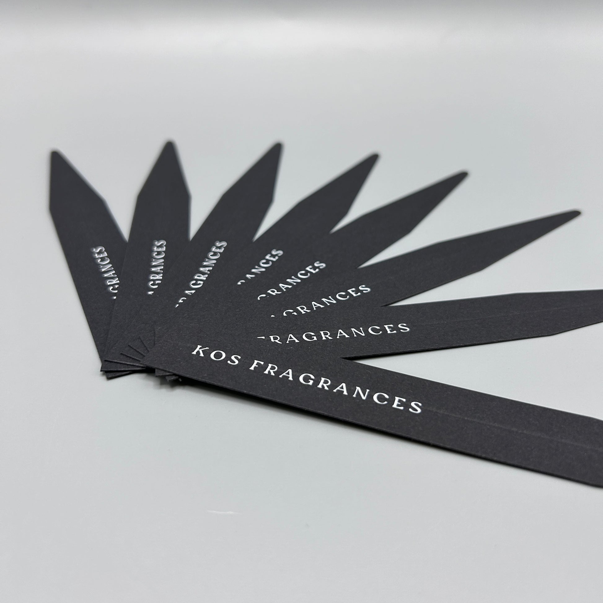 Black smelling strips with 'KOS FRAGRANCES' branding on a gray background